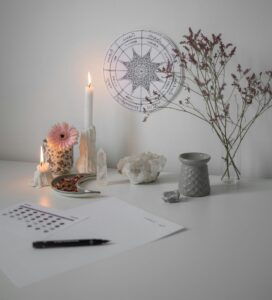 A serene desk featuring candles, flowers, and a tarot chart for a calm atmosphere.